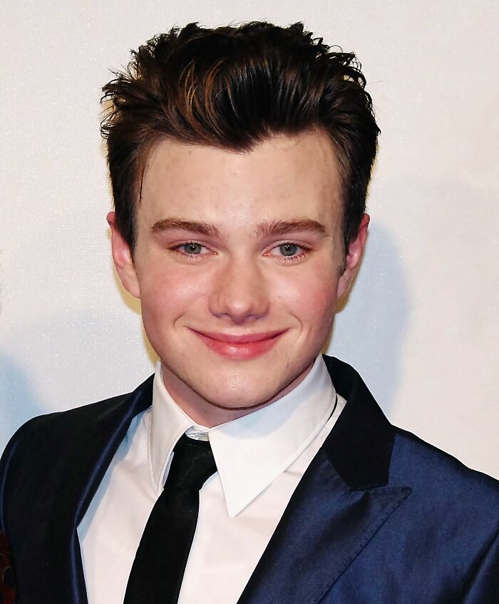Portrait of Chris Colfer smiling in a suit and tie at a formal event