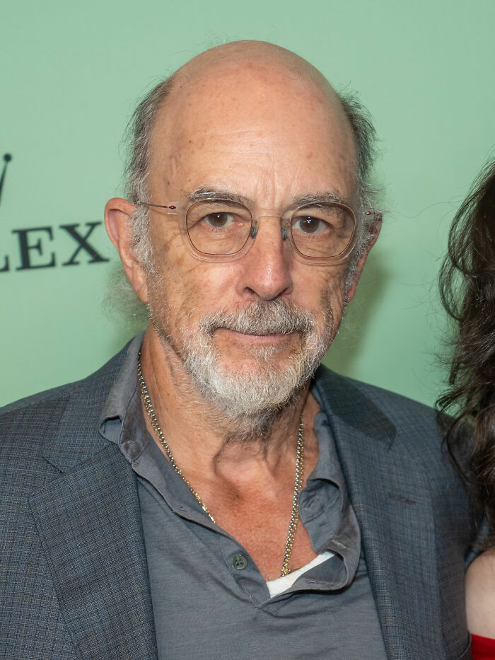 Close-up photo of Richard Schiff wearing glasses and a blazer at an event
