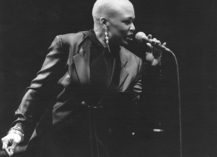 Dee Dee Bridgewater performing live on stage with microphone in black and white photo