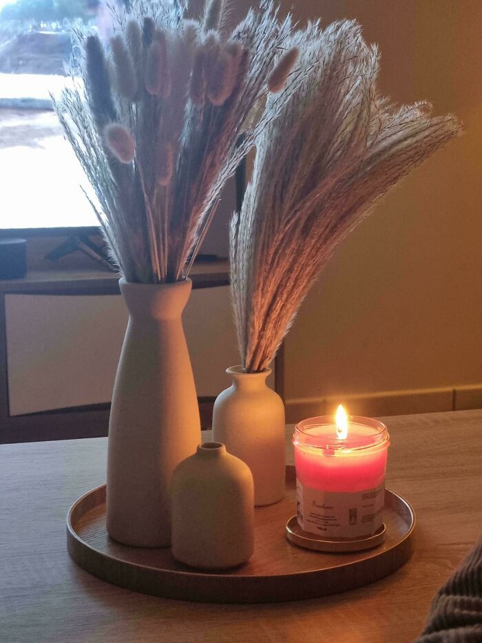 Cozy home decor with vases and a lit candle on a wooden tray indoors