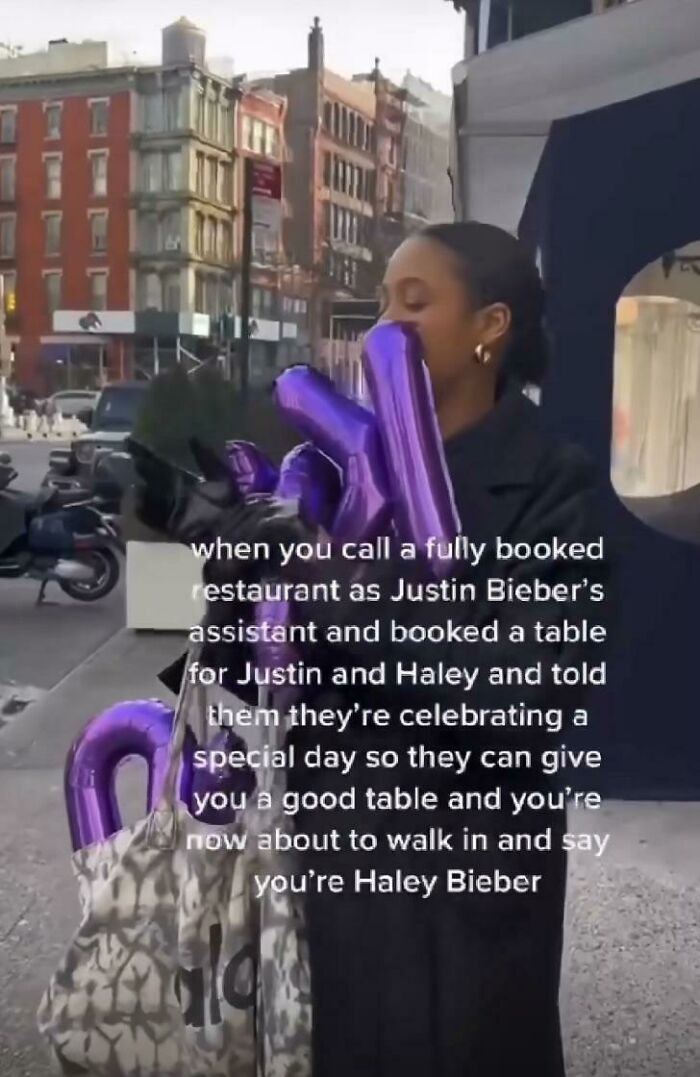 Woman holding balloons joking about booking a restaurant as Haley Bieber