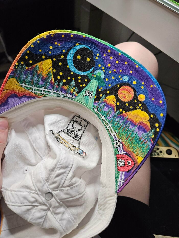 A vibrant, hand-painted baseball cap featuring a night sky scene, demonstrating artistic talent and a touch of magic.