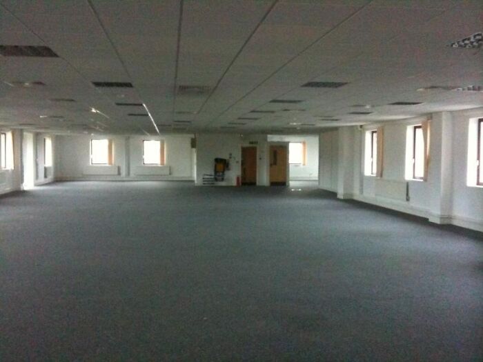 Empty office space with carpet and multiple windows representing Backrooms levels