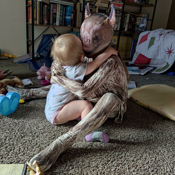 Child hugging person in a realistic pig costume indoors funny fail