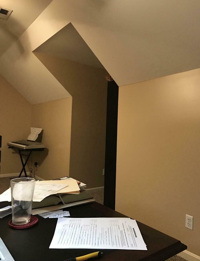 Hidden face peeking from corner in ordinary room with desk