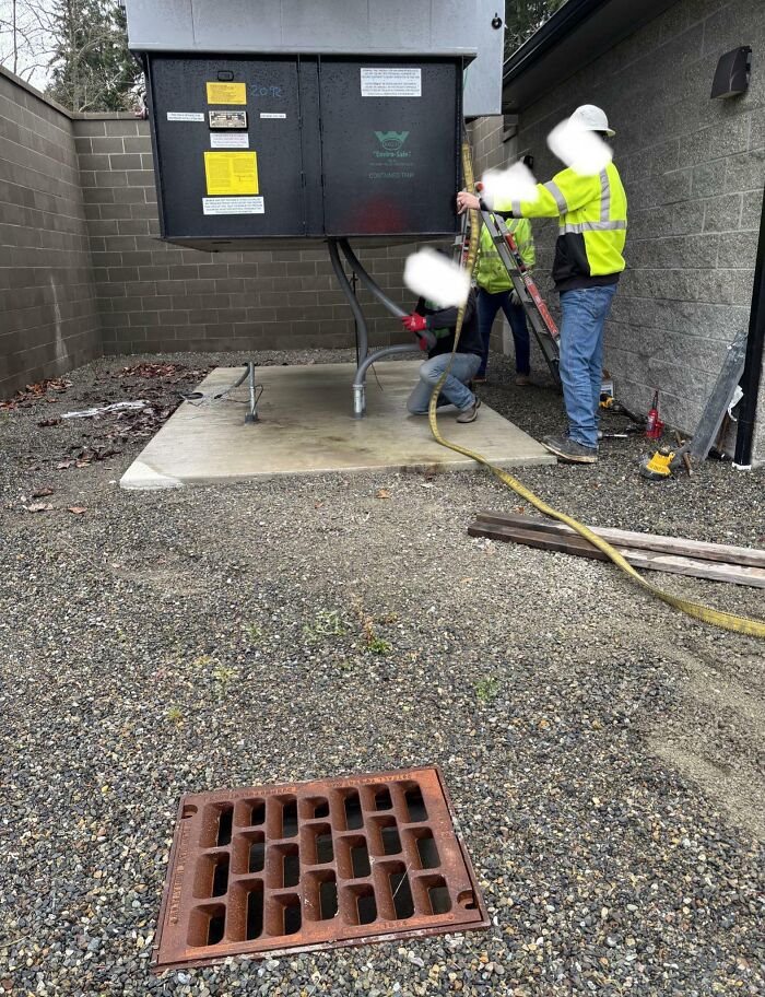 Workers operating electrical box near drainage grate in risky survival environment