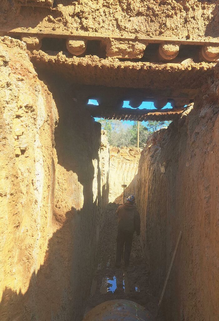 Worker standing in a deep trench under unstable excavation site