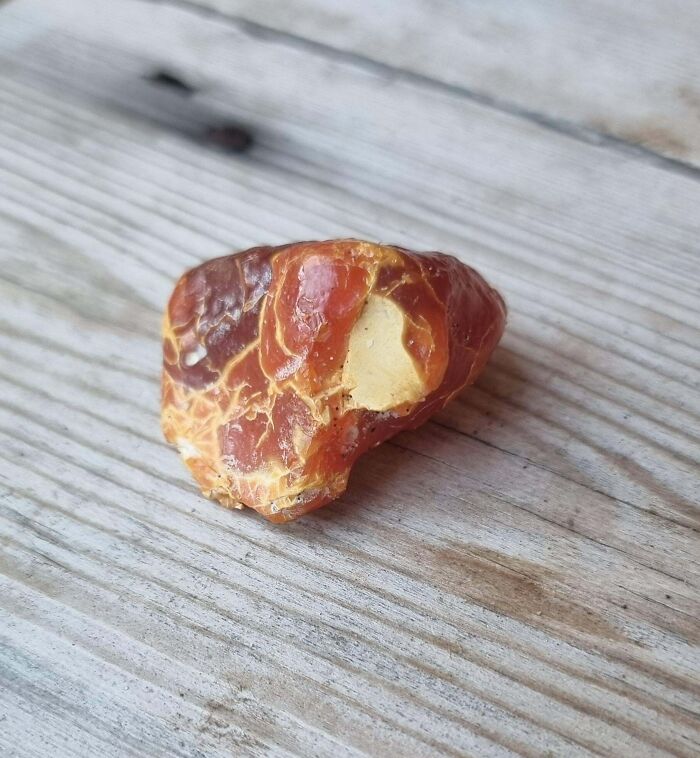 Close-up of an amber stone on wooden surface showing detailed texture