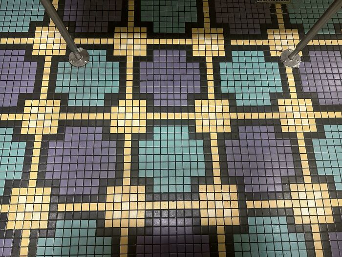 Patterned tile floor with colorful squares and metal poles