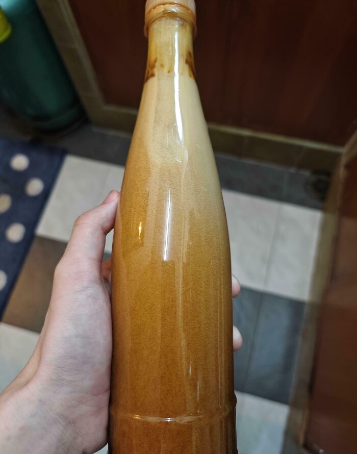 Hand holding old bottle showing sediment risk in survival supply