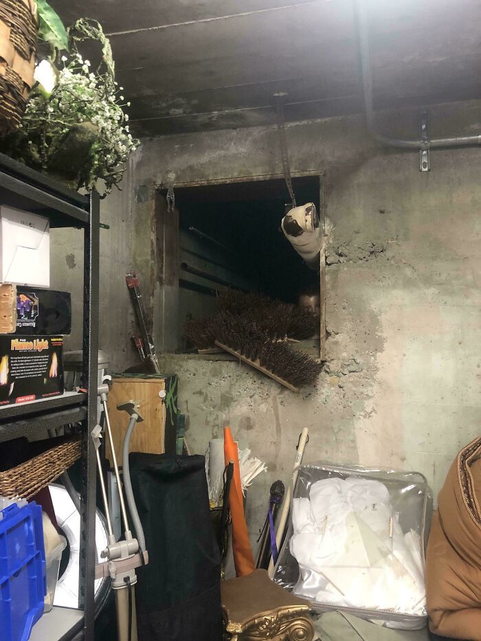 Cluttered basement with a hidden face peeking through a dark window opening