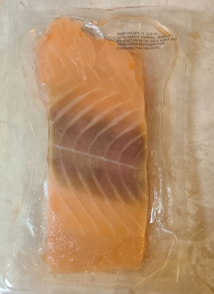 Vacuum-sealed salmon fillet with discoloration inside packaging