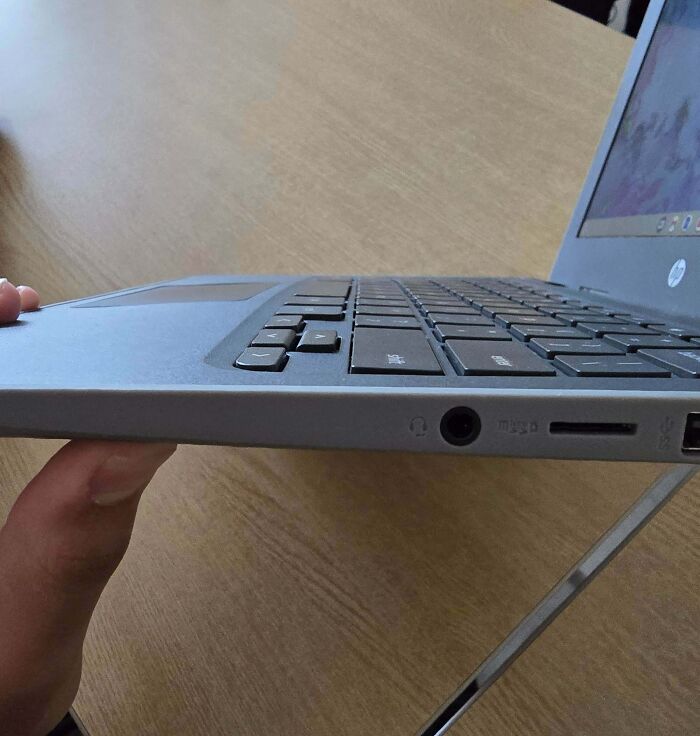 Side view of laptop held by hand showing headphone jack and micro SD slot