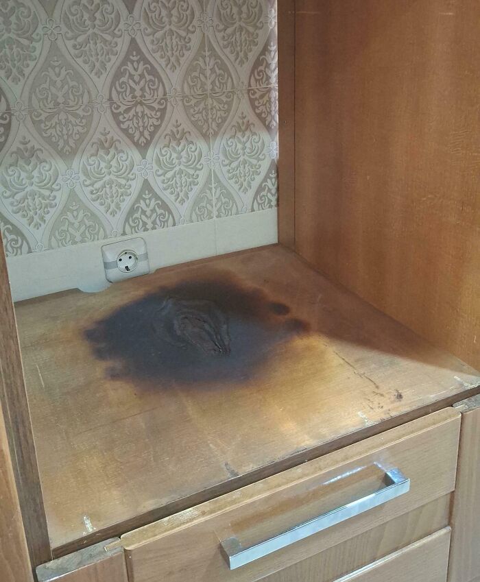 Burnt wooden surface near electrical outlet in kitchen cabinet