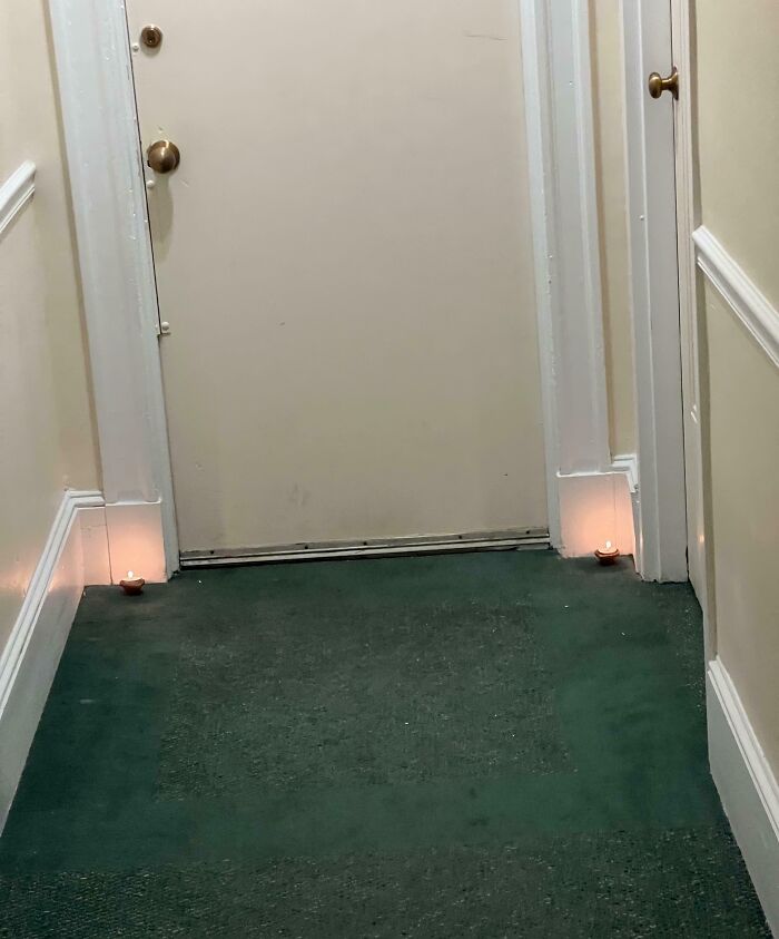 Hallway with small candles dangerously placed near door on green carpet risky survival situation