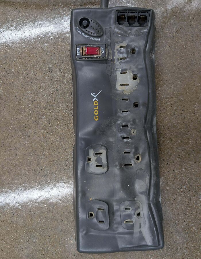 Melted and damaged black power strip showing extreme electrical risk