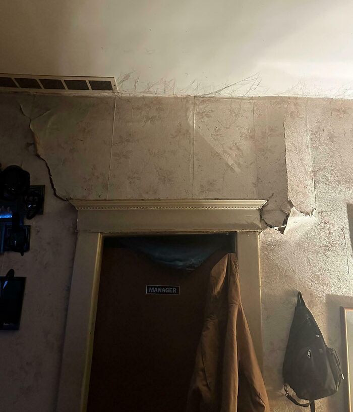 Peeling wallpaper around door labeled manager in neglected room risky survival situation