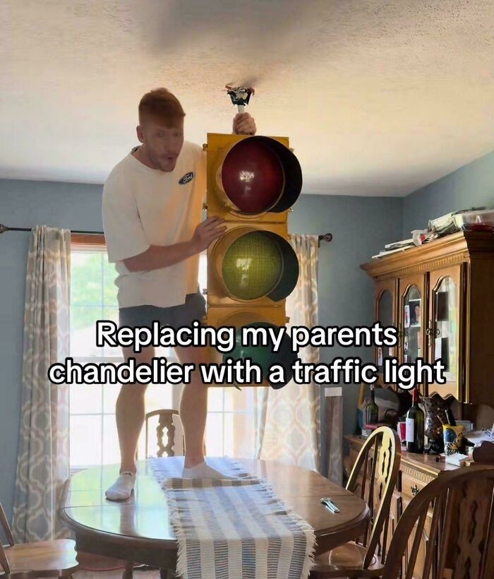 Man replacing chandelier with a traffic light in living room humor screenshot