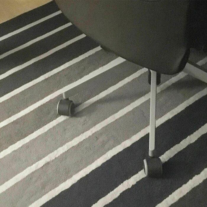 Office chair wheels blending with striped carpet pattern detail