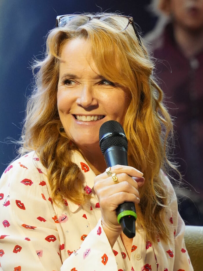 Lea Thompson smiling and holding a microphone during an interview or event