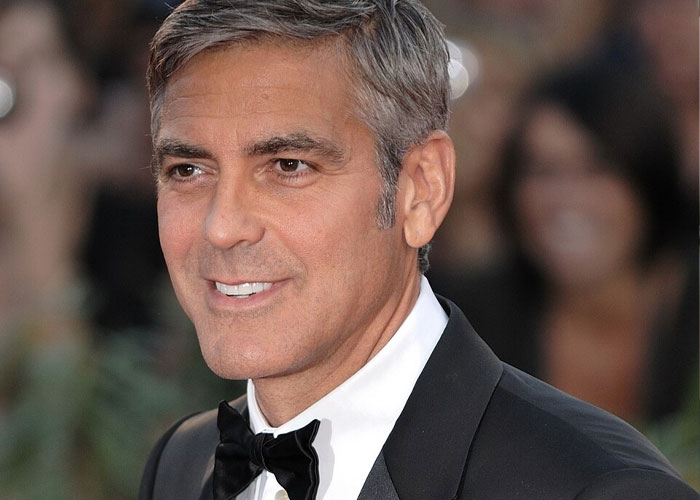 Close-up of a smiling George Clooney in a tuxedo, challenging US stereotypes with his iconic Hollywood persona.