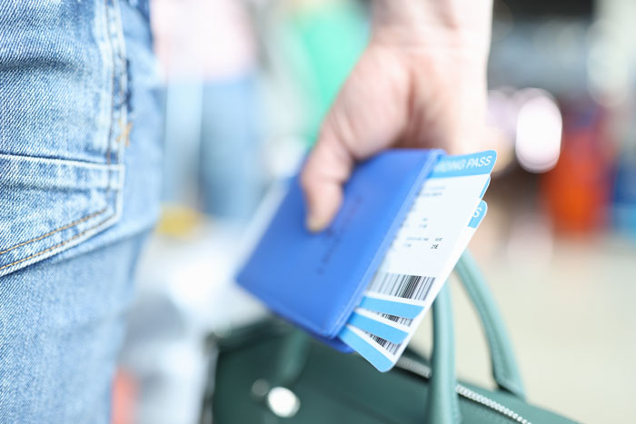 Close-up of hand holding blue boarding pass showing travel PR fail