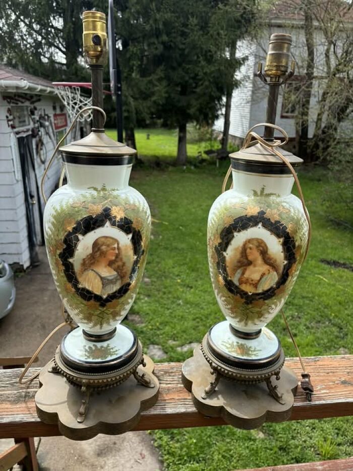 Pair of vintage secondhand porcelain table lamps with painted portraits on wooden deck