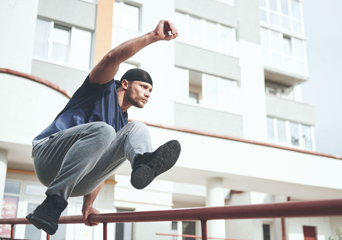 Man doing parkour jump over railing in urban environment