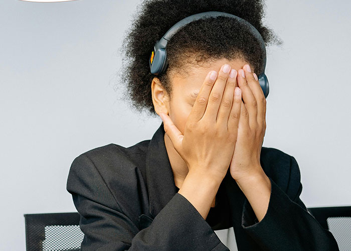 Stressed woman covering her face wearing headphones