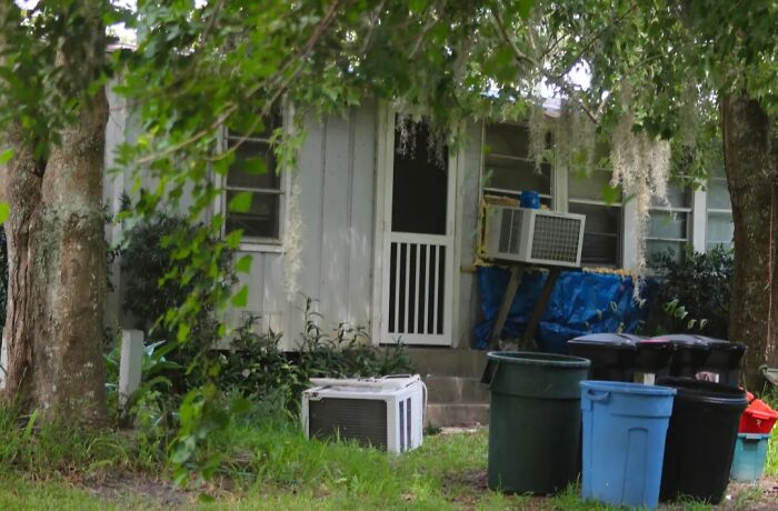 House exterior with air conditioning unit and trash bins outside in yard