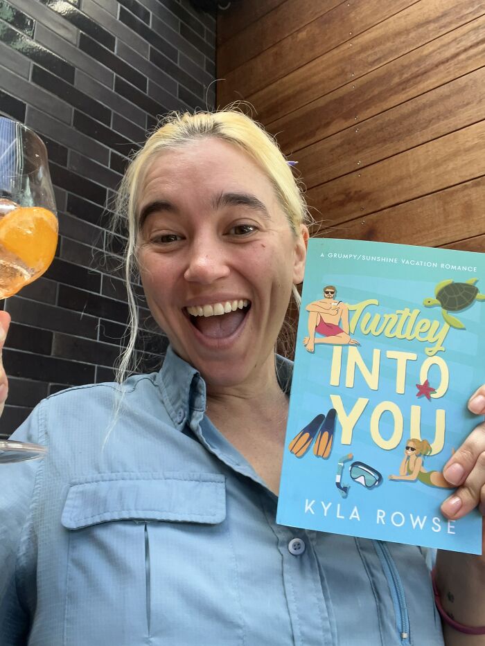 Woman celebrating with book and drink after quitting a horrible job