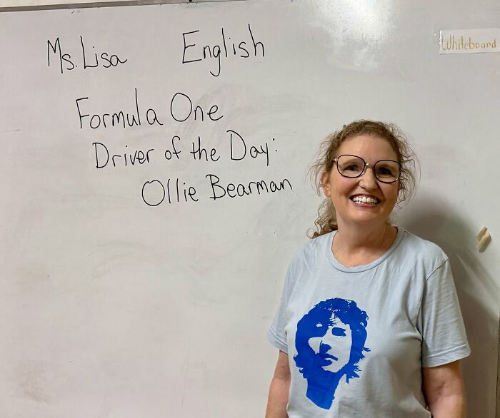 Smiling woman standing by whiteboard with message about Formula One driver Ollie Bearman