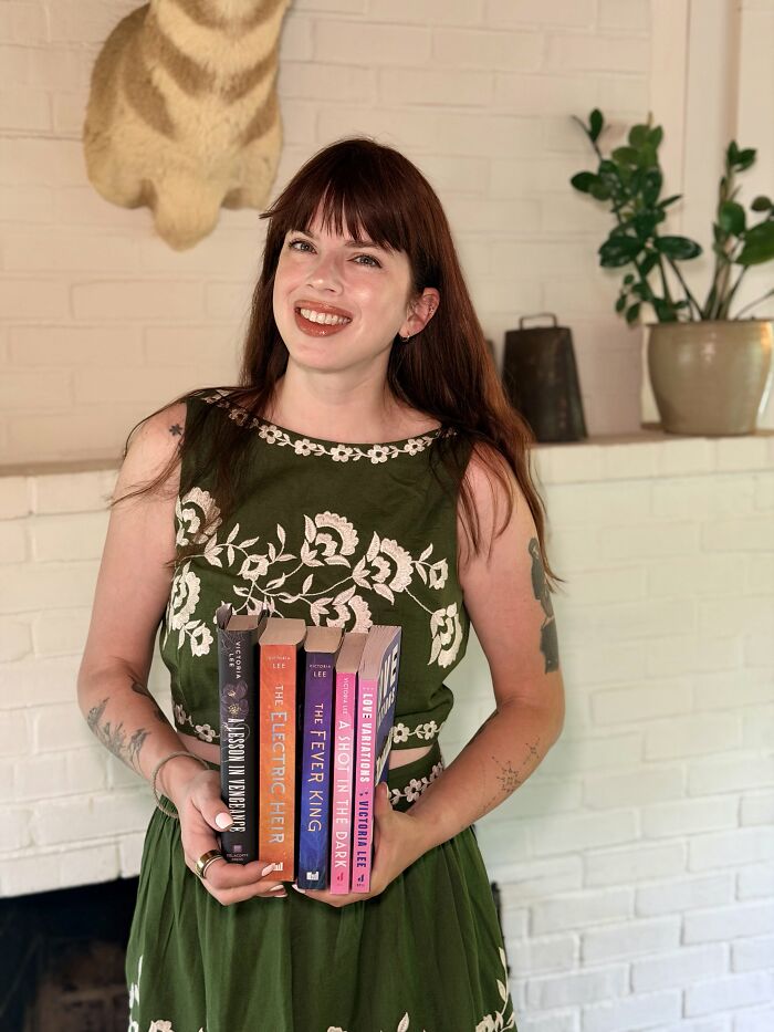 Smiling woman holding books wearing green embroidered dress