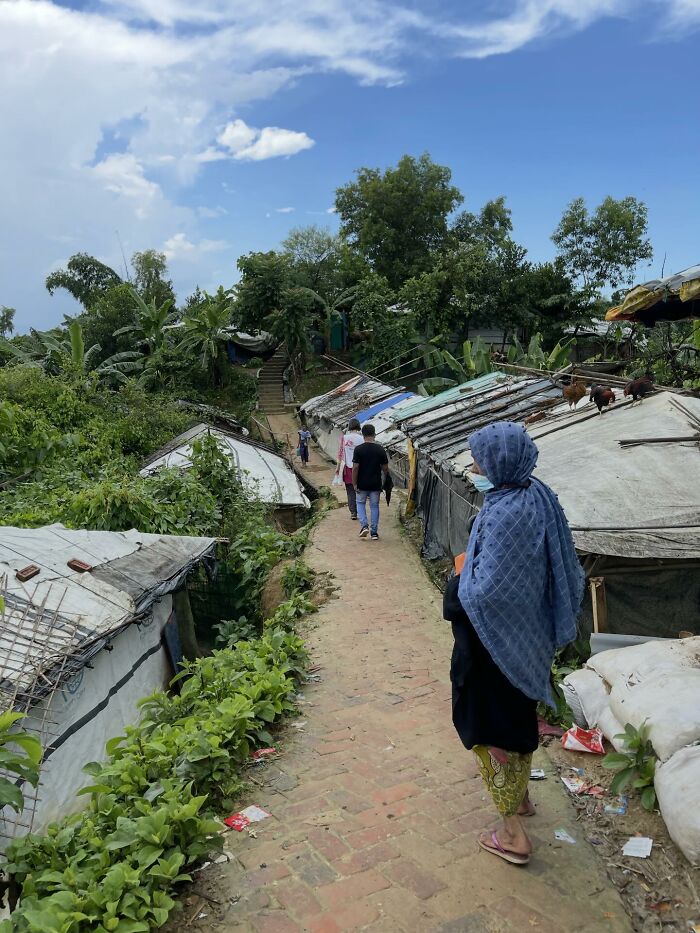 People walking through a rural village pathway under blue sky