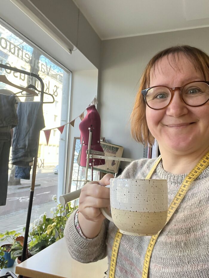 Smiling woman seamstress with mug in creative workspace quitting job