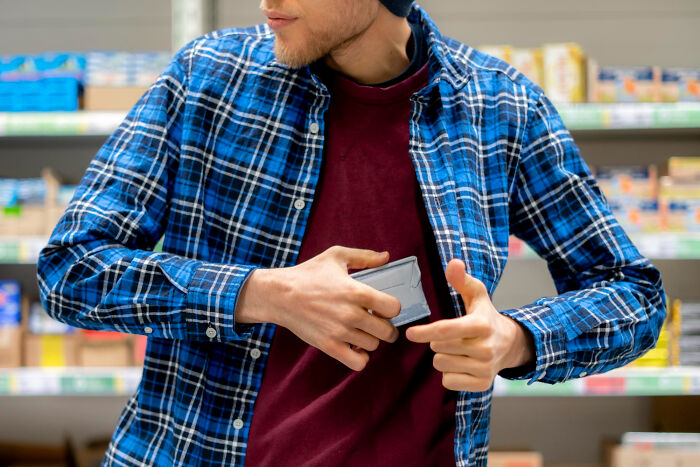 Man in store suspiciously hiding wallet, depicting theft