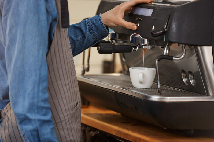 Barista making coffee with espresso machine on auto pilot