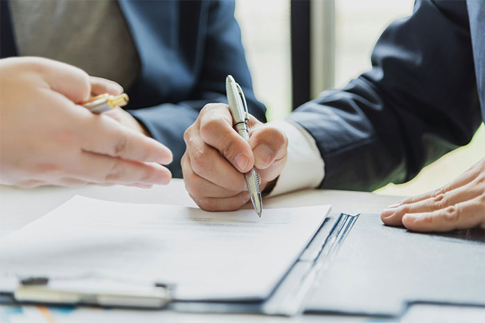 Businessman signing contract during a meeting illustrating boss losing millions Businessman signing contract during a meeting illustrating boss losing millions