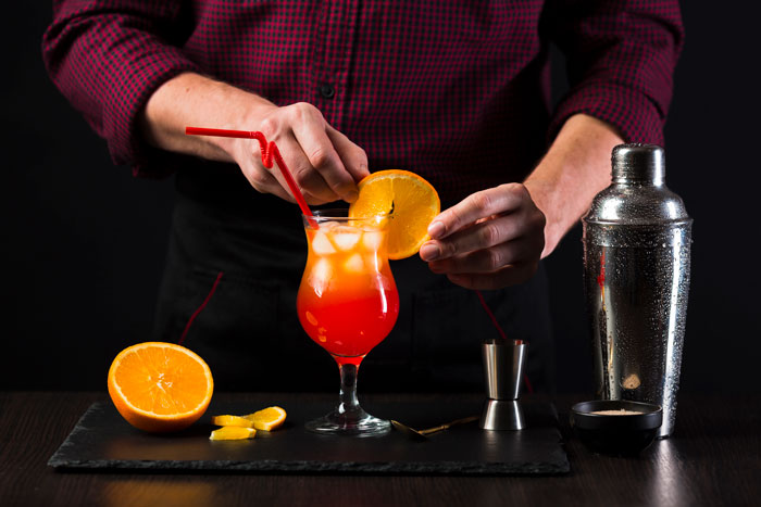 Bartender garnishing artisinal cocktail with orange slice