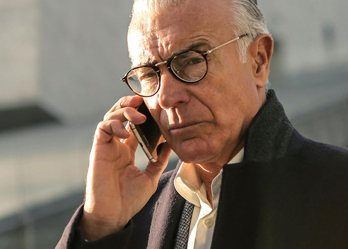 Older man with glasses making a serious phone call outdoors