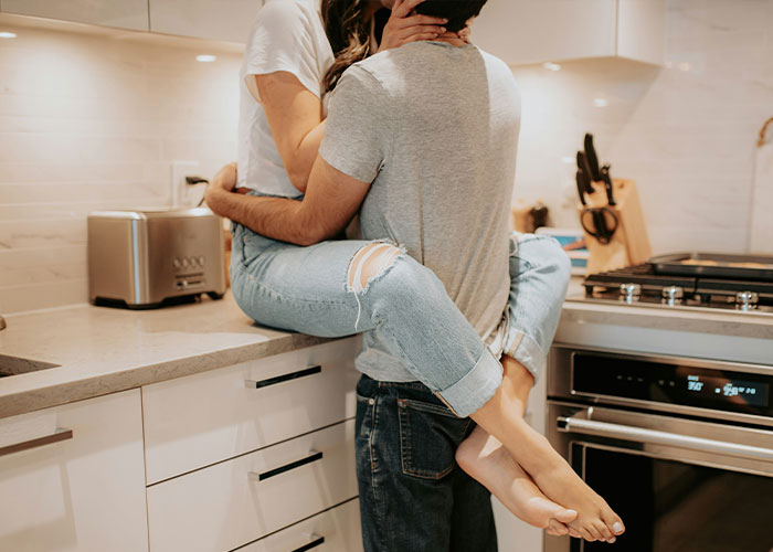 Couple embracing intimately in kitchen with modern appliances
