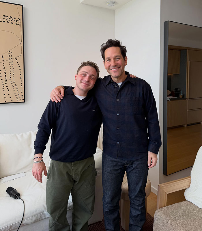 Paul Rudd posing with a friend indoors smiling casually