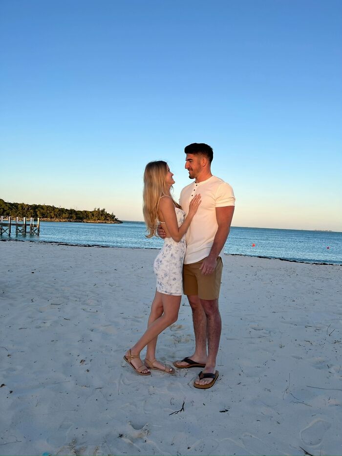 A couple embracing on a sandy beach at sunset, gazing into each other's eyes. Romantic engagement story.