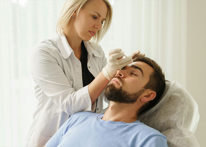Woman dermatologist treating man's face, related to male celeb appearances