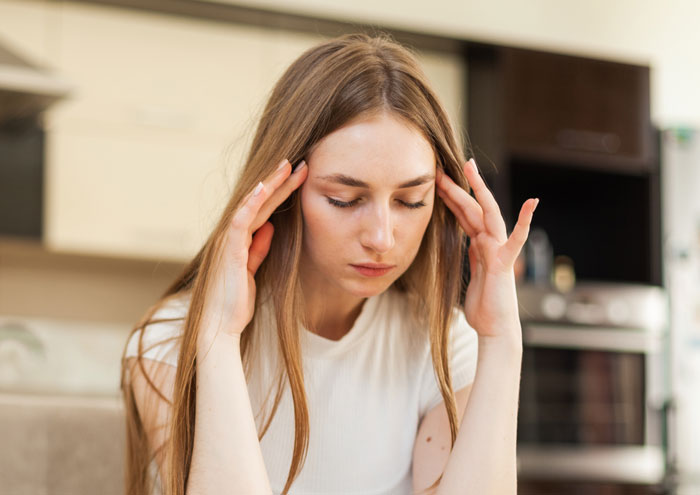 Stressed woman holding her head in kitchen Stressed woman holding her head in kitchen