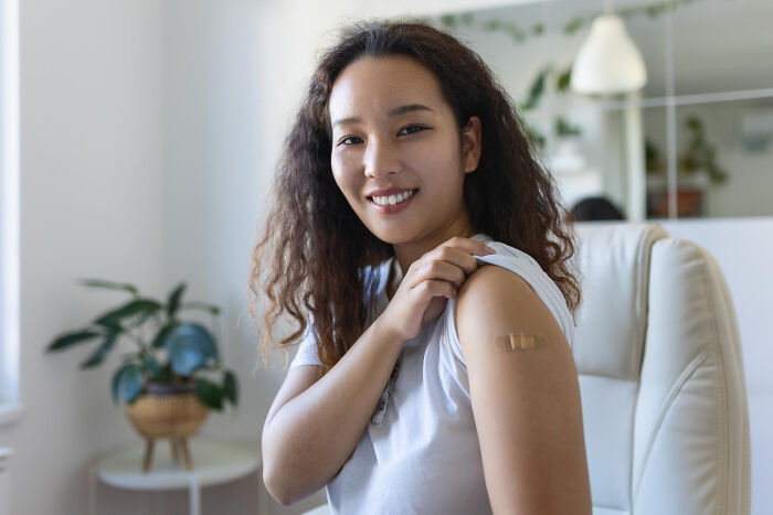 Woman showing arm with bandage after vaccination
