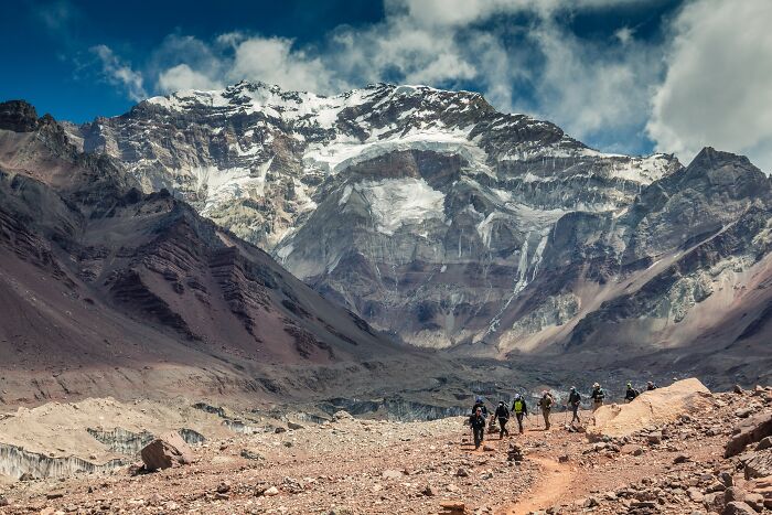 Hikers walking toward snowy mountain with stunning rugged landscape views
