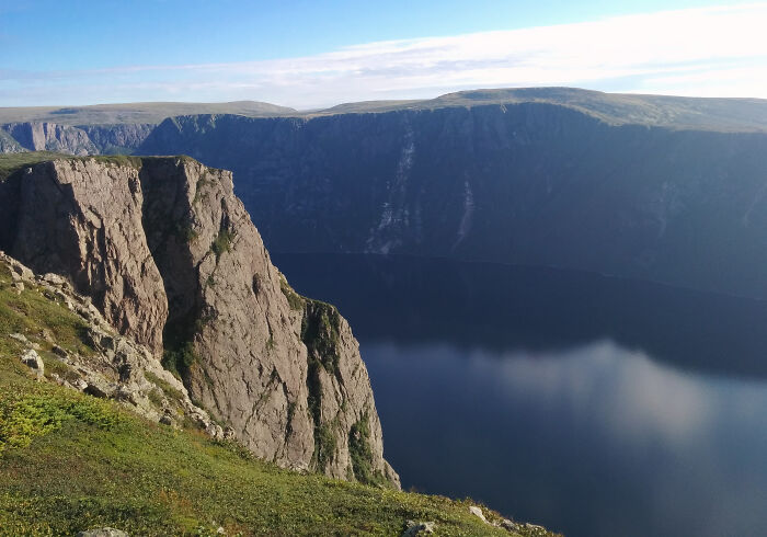 Cliffside overlooking deep blue fjord with green grass stunning natural views