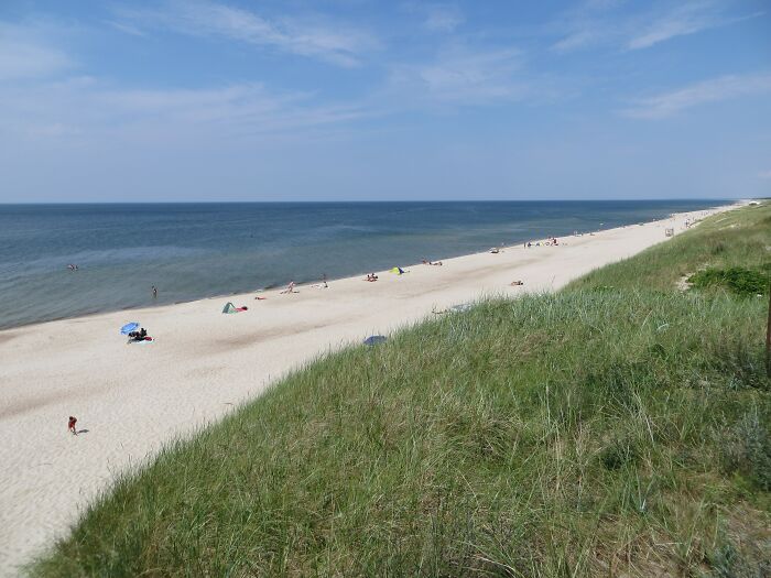 Wide sandy beach with grassy dunes and ocean horizon