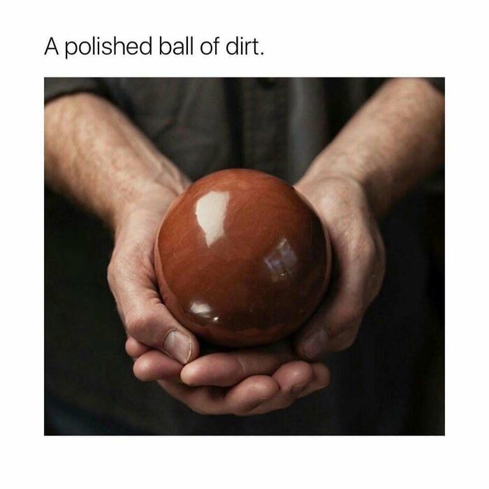 Polished brown ball held in hands resembling a smooth dirt sphere